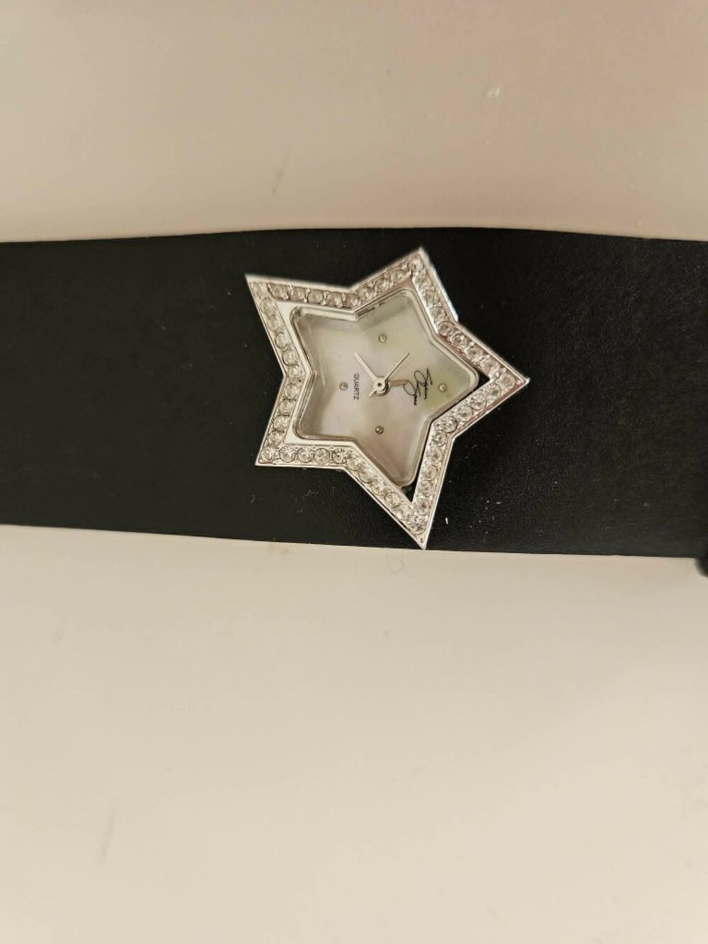 Watch with a star framed with rhinestones, a leather band, by Suzanne Sommers.